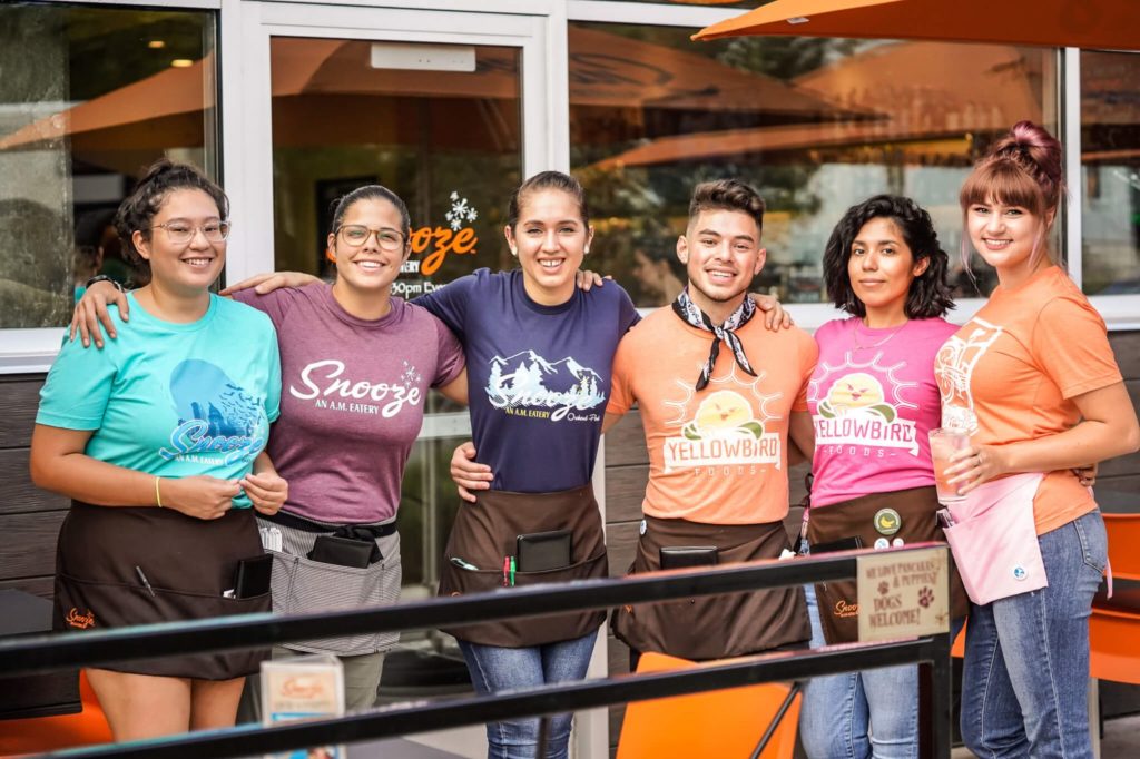 A Group Of Snooze Employees Stand Together On The Restaurant Patio